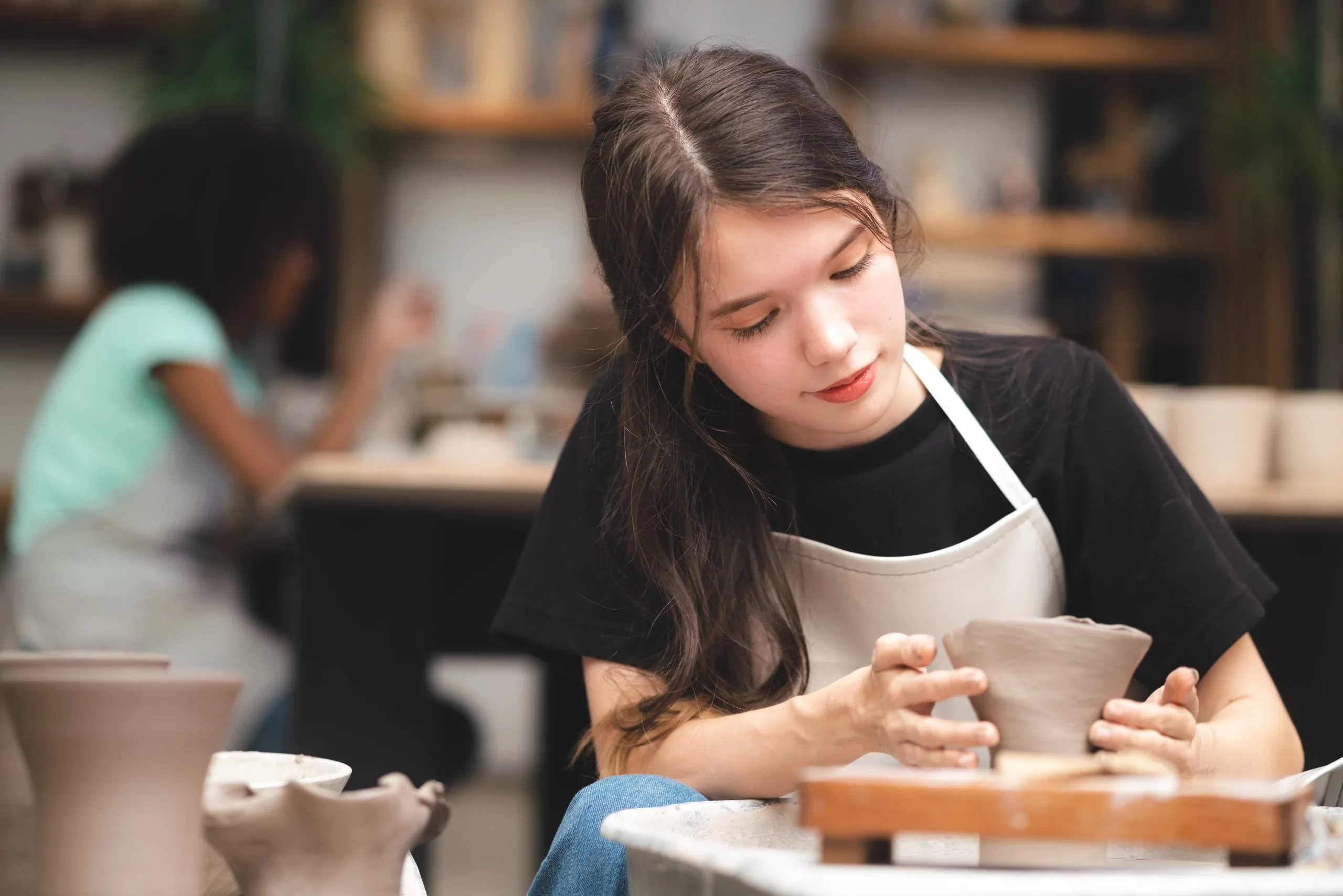 A teen girl works at a potter’s wheel 